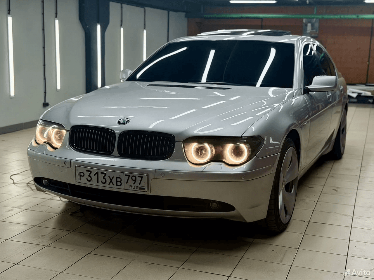 Светлый BMW 745i в помещении, вид спереди сбоку
