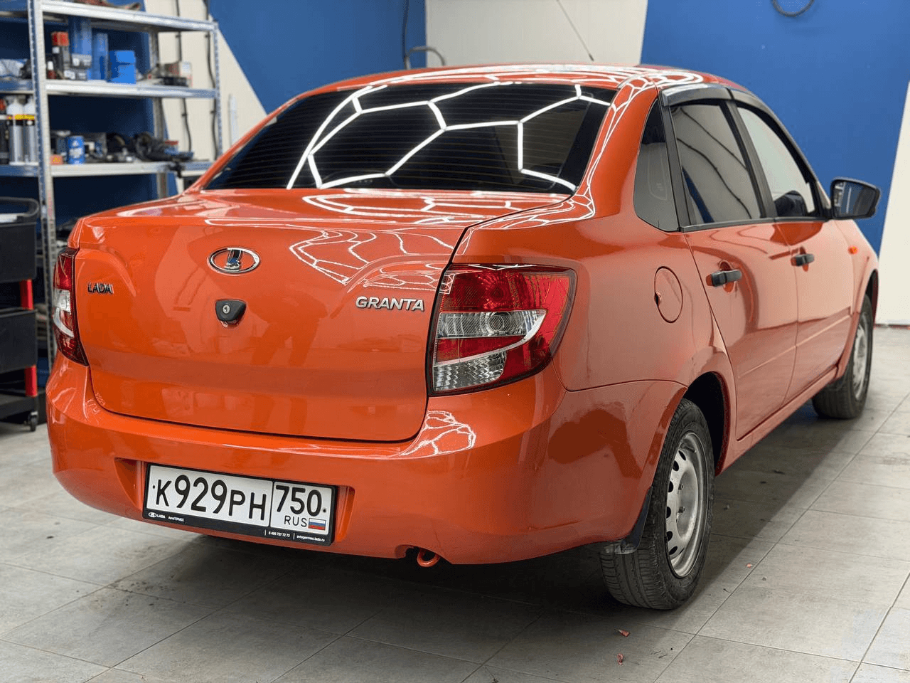 Оранжевая Lada Granta в студии, общий вид сзади сбоку